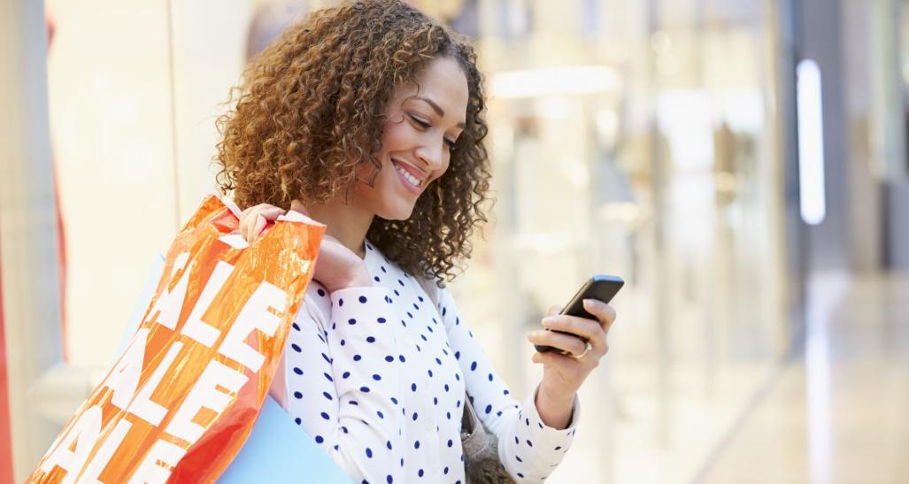 Individuals shopping and looking at her phone.