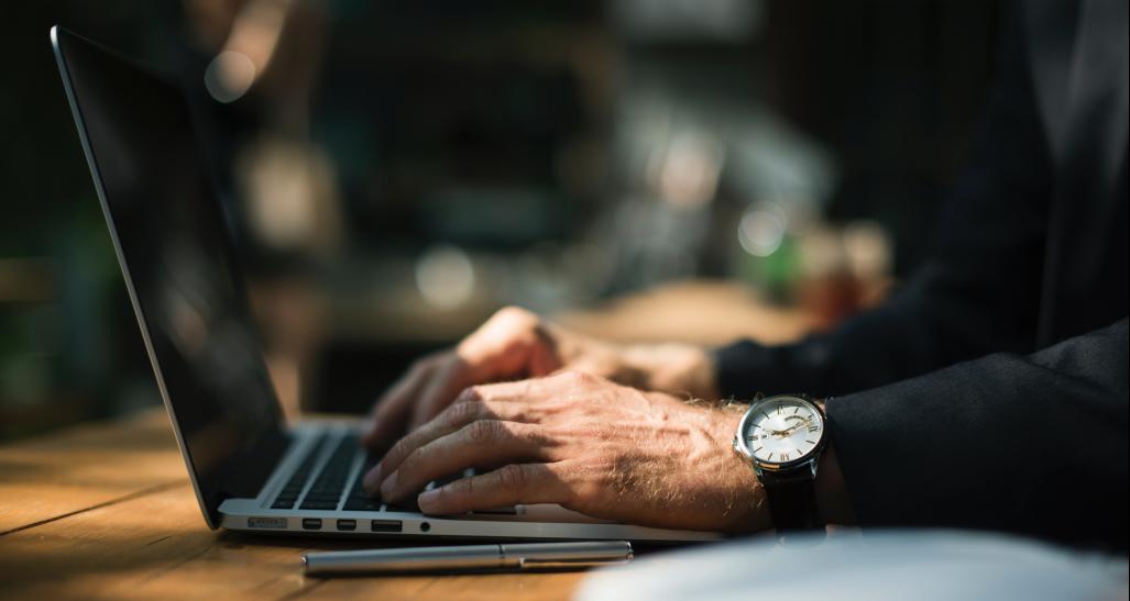 a closeup image of a guy's hands on a laptop