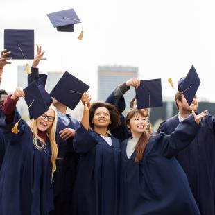 College students throwing caps in the air at graduation ceremony