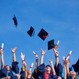 Group of kids throw their caps in the sky