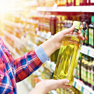 A woman holds cooking oil in grocery aisle