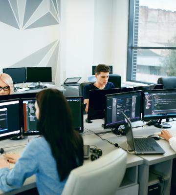 Group of people on computers around a table at work