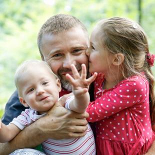 Father playing outdoors with two children