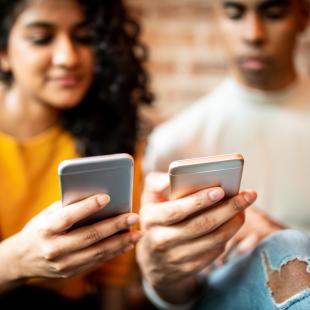 A man and a woman look at their smart phones