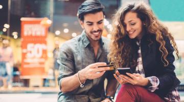 A couple looks at phone outside of a store