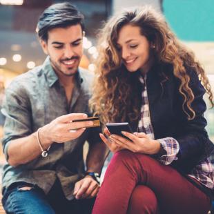 A couple looks at phone outside of a store