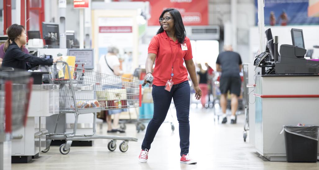 Retail employee at warehouse store pulling shopping cart