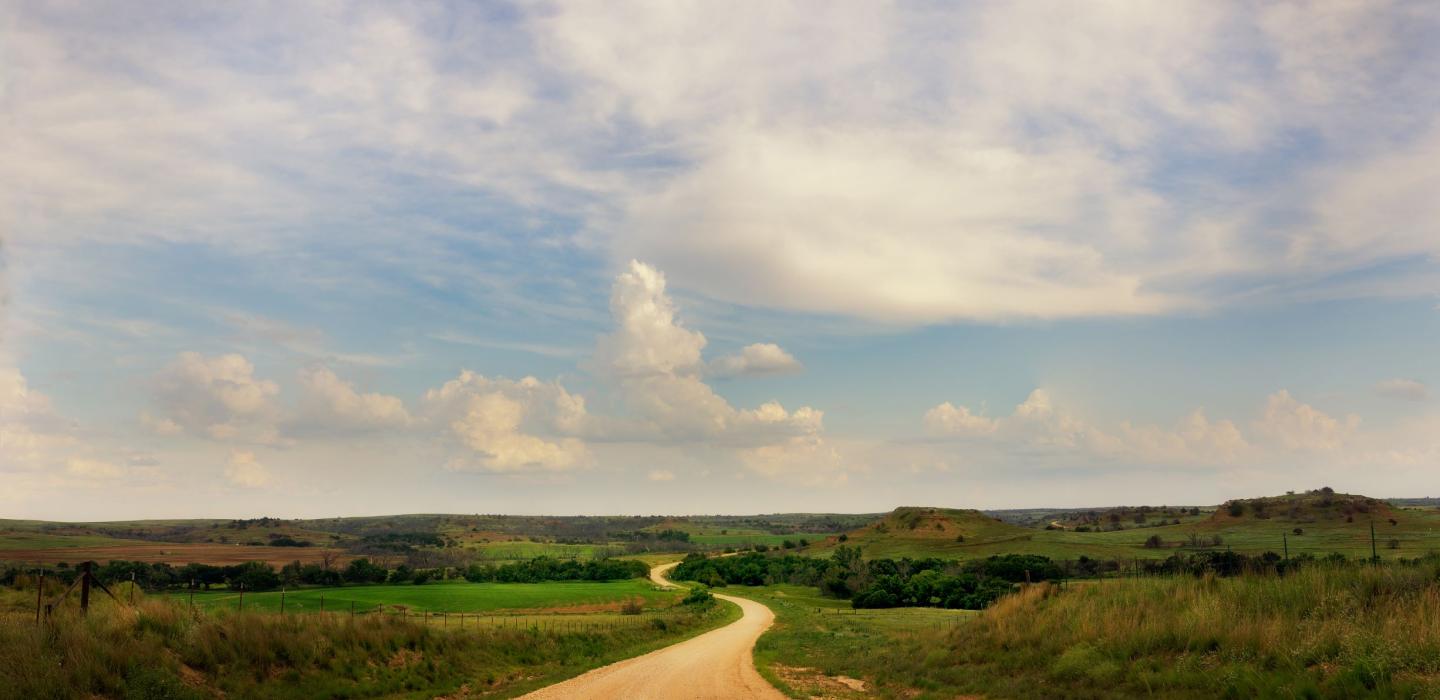 A long road in Kansas with farmhouses.