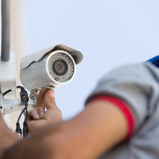 Man installing security camera on wall outside