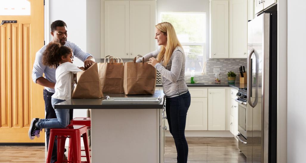 a family is shown in the kitchen after grocery shopping