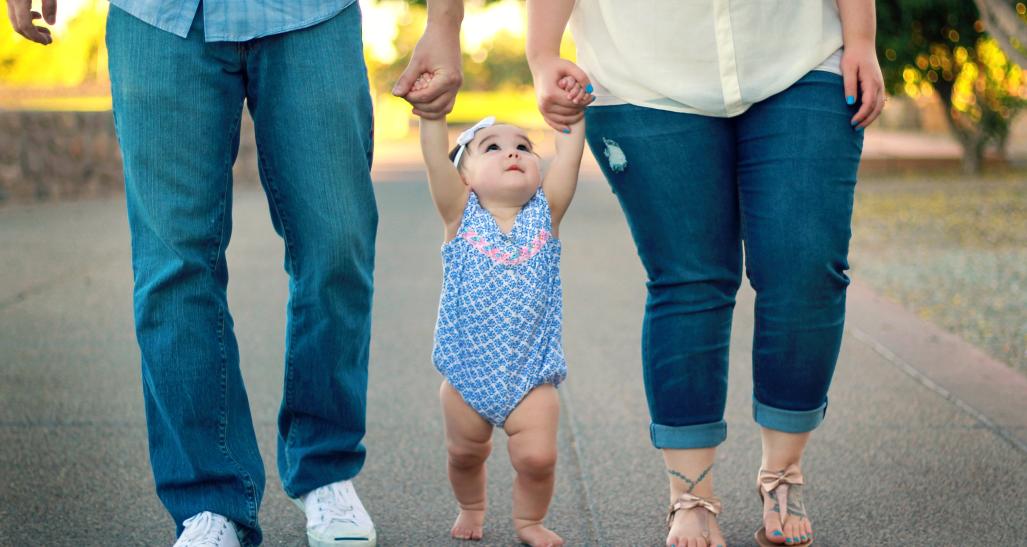 a mother and a father walking their toddler baby