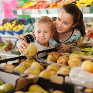 Mother and child shopping for groceries choosing fruit
