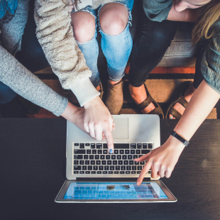 Group of people point and look over a laptop