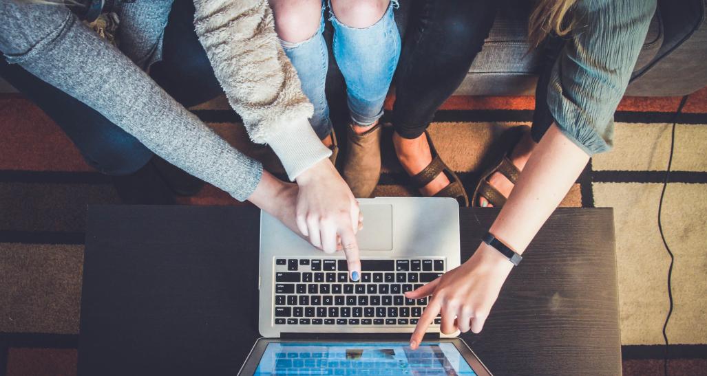 Group of people point and look over a laptop