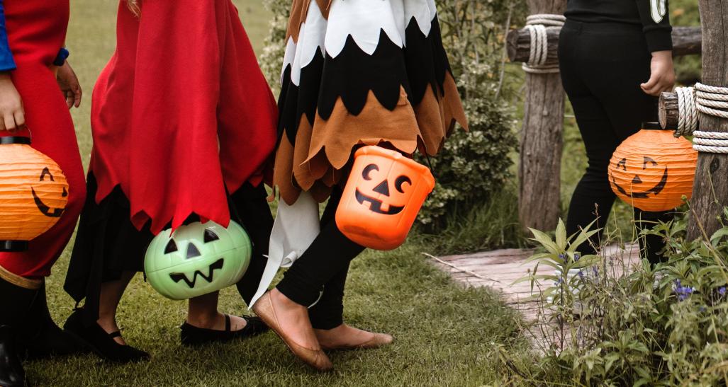 three kids holding their baskets during trick or treating time on halloween