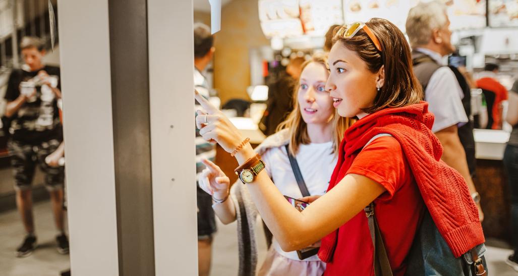 Individuals using technology to order at restaurant.