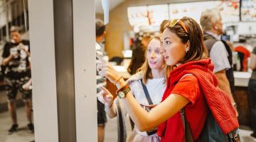 Individuals using technology to order at restaurant. 