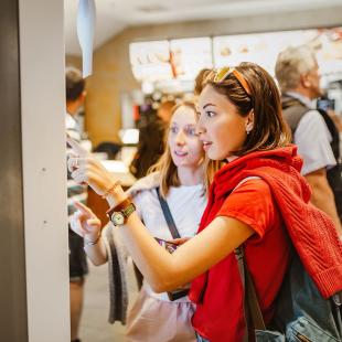 Individuals using technology to order at restaurant. 