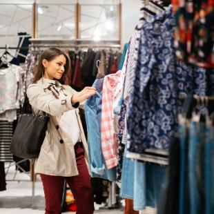 a woman contemplates getting a shirt in a store