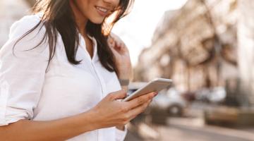 woman looks at her phone on the street