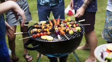 A group of people around a charcoal grill