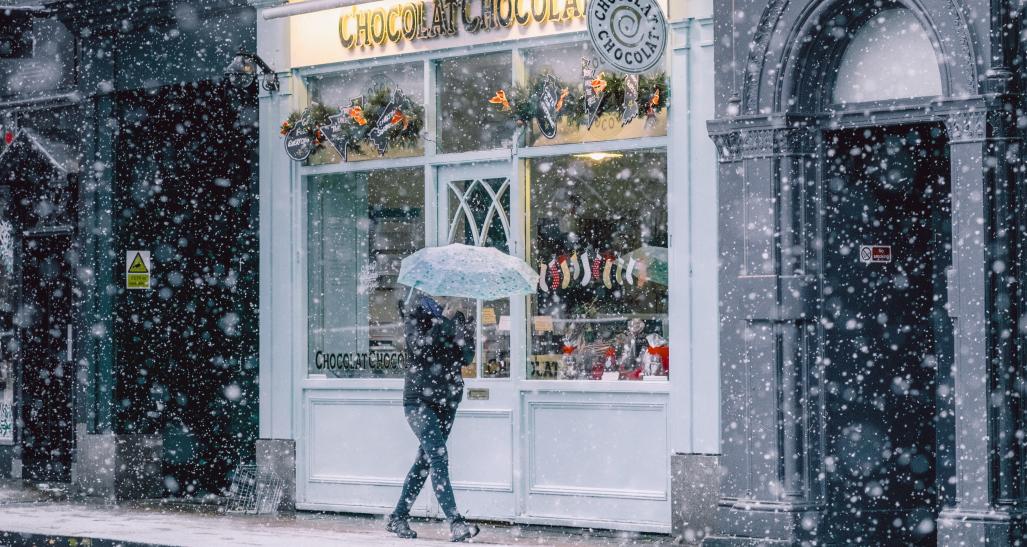 woman in a snowy town walking by stores
