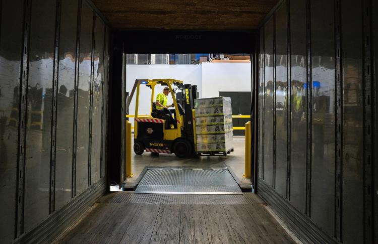 a guy is shown loading boxes from a dock into a truck
