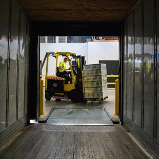 a guy is shown loading boxes from a dock into a truck