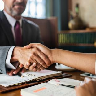 a man and a woman are shaking hands at a table