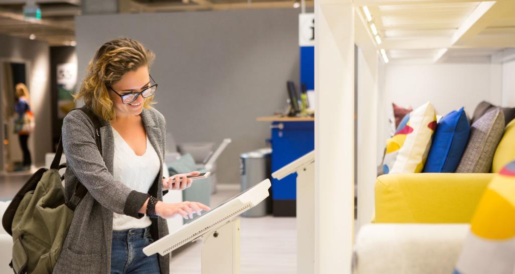 woman stands over computer screen selecting furniture options in furniture store