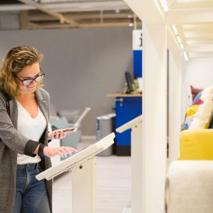 woman stands over computer screen selecting furniture options in furniture store