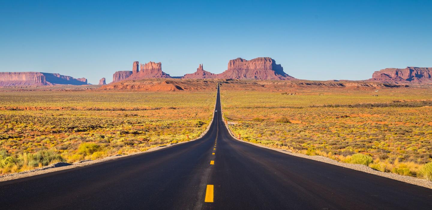 An open road with mountain ranges in Utah.